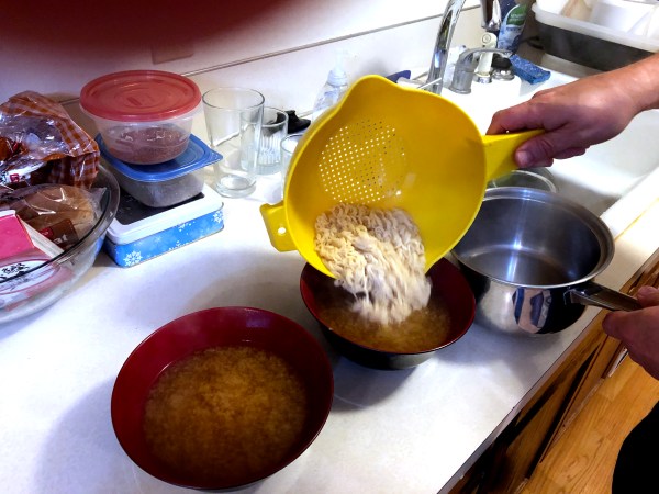 Adding the ramen noodles to the stock and tare in the serving bowl.